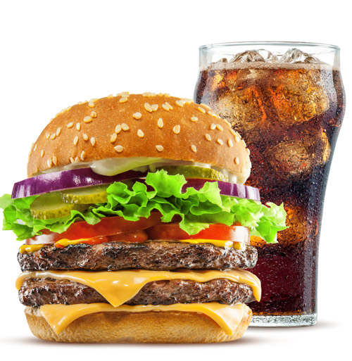A hamburger next to a glass of cola.